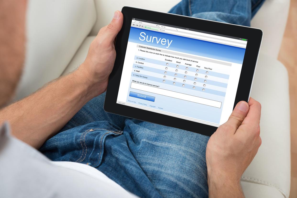 Man on sofa with digital tablet showing survey form