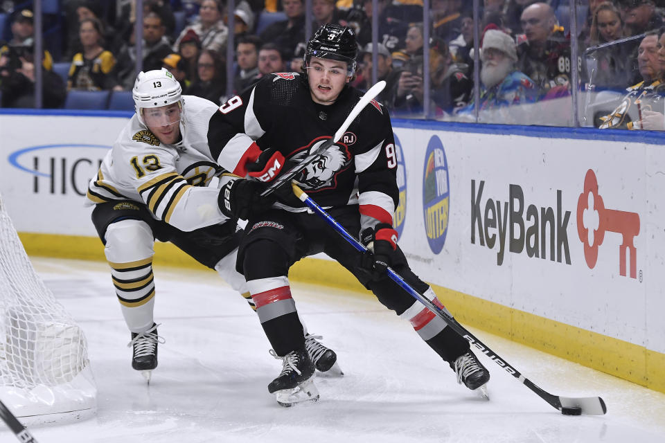 Buffalo Sabres left wing Zach Benson, right, shields the puck from Boston Bruins center Charlie Coyle during the first period of an NHL hockey game in Buffalo, N.Y., Wednesday, Dec. 27, 2023. (AP Photo/Adrian Kraus)