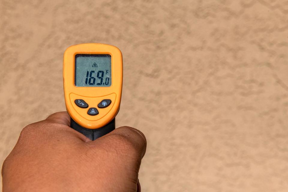 A hand holding a yellow thermometer that reads 169 degrees