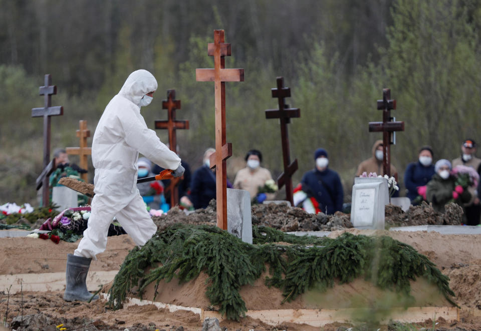 Mourners wear face masks at a cemetery