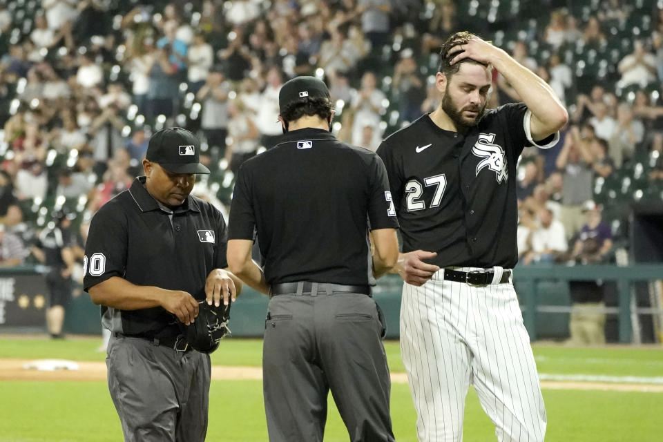 Umpire Adrian Johnson (80) checks Chicago White Sox starting pitcher Lucas Giolito's glove as umpire John Tumpane checks his cap after Giolito was taken out of the baseball game in the seventh inningTuesday, June 29, 2021, in Chicago. (AP Photo/Charles Rex Arbogast)