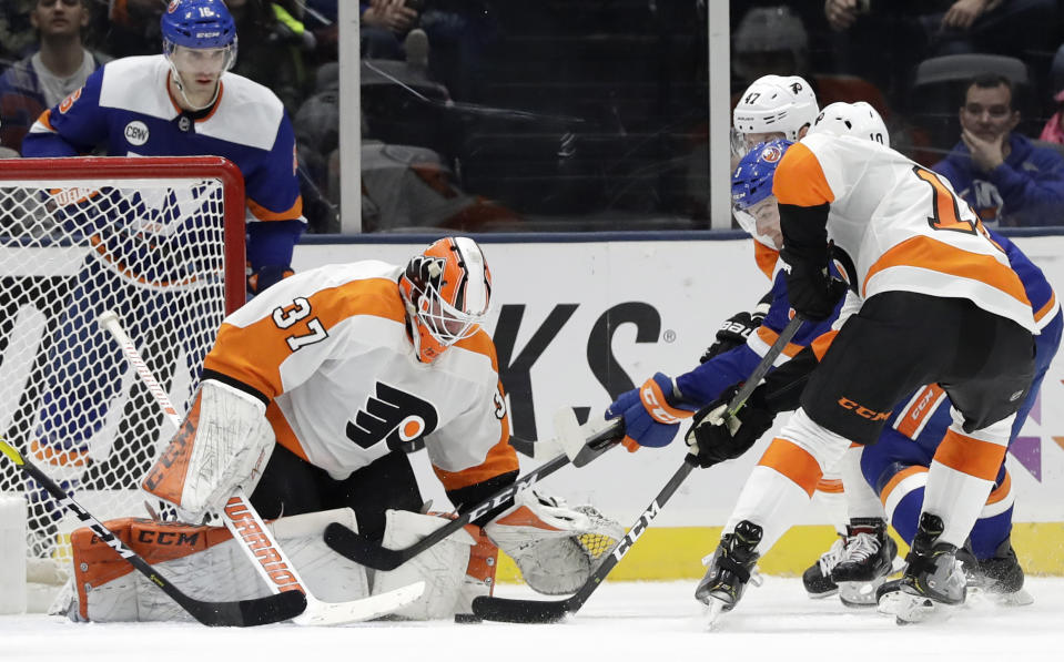 New York Islanders defenseman Adam Pelech (3) advances the puck in front of Philadelphia Flyers goaltender Brian Elliott (37) before scoring a goal with Flyers center Corban Knight (10) and Flyers defenseman Andrew MacDonald (47) defending during the third period of an NHL hockey game, Sunday, March 3, 2019, in Uniondale, N.Y. The Flyers defeated the Islanders 4-1. (AP Photo/Kathy Willens)