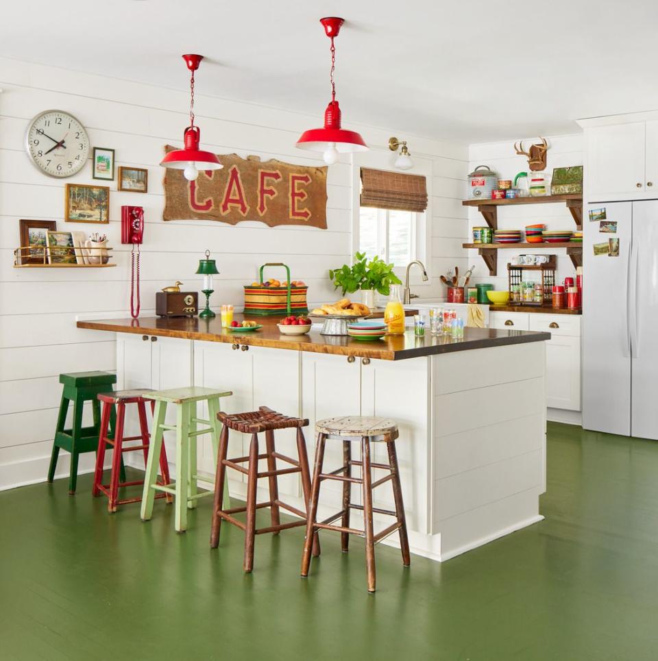 a kitchen with painted green floors and a vintage vibe thanks to mix match barstools and bright colors and a cafe sign