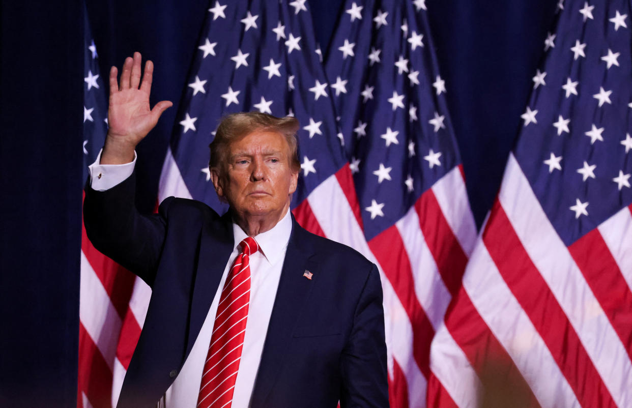 Donald Trump, standing in front of U.S. flags, gestures during a campaign rally.
