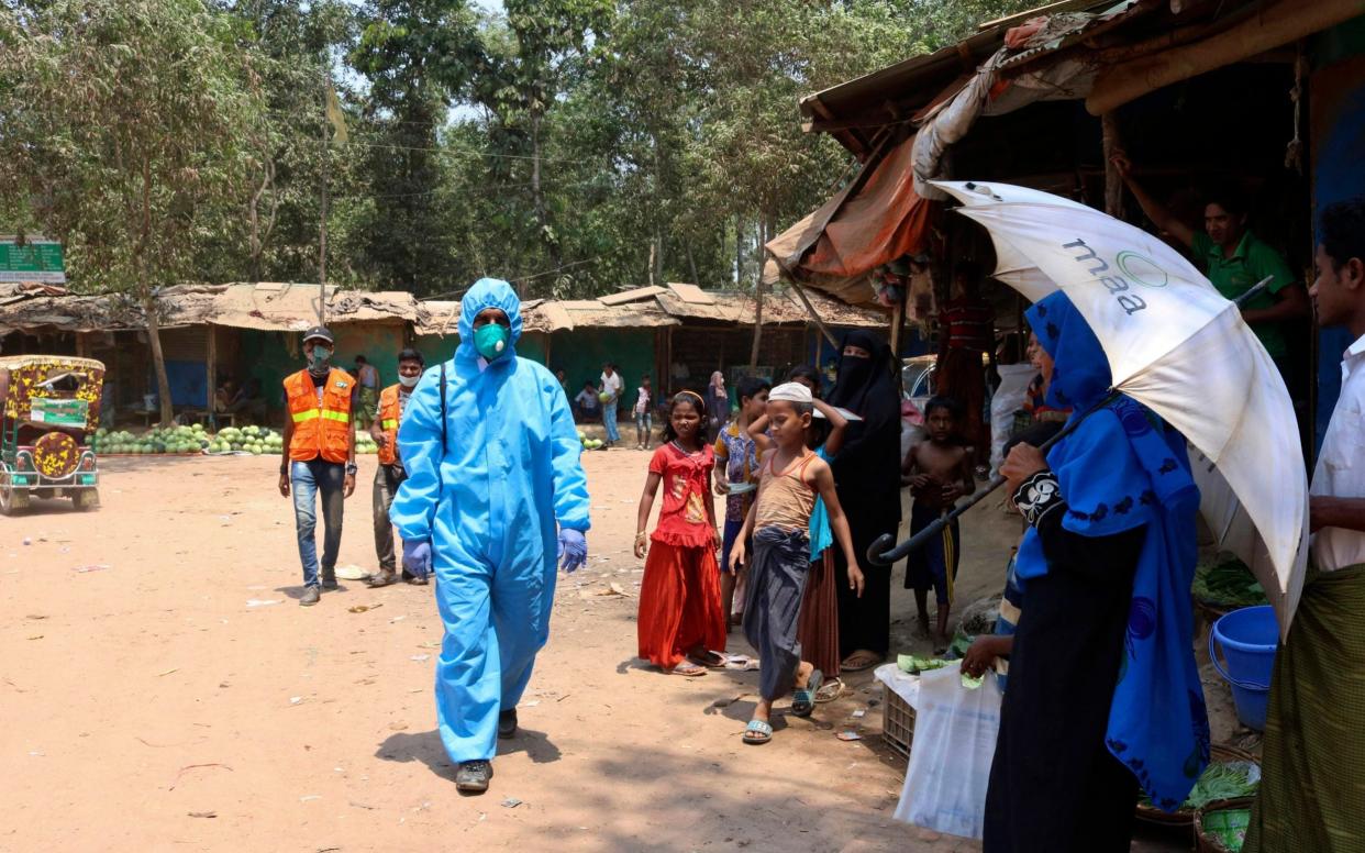 A health worker wearing a hazmat suit walks through the Cox's Bazar Rohingya camp, the largest refugee camp in the world -  Shafiqur Rahman/AP