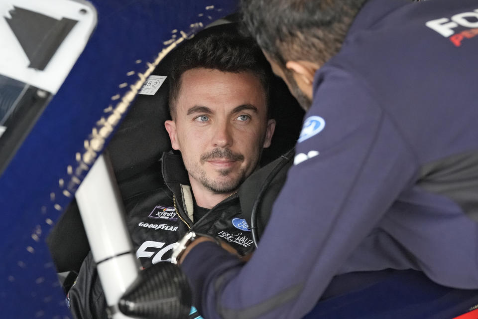 Race car driver and actor Frankie Muniz, left, talks to a crew member before a practice run Friday, Feb. 16, 2024, at Daytona International Speedway in Daytona Beach, Fla. Muniz will attempt to make his NASCAR Xfinity Series debut Saturday. (AP Photo/Chris O'Meara)