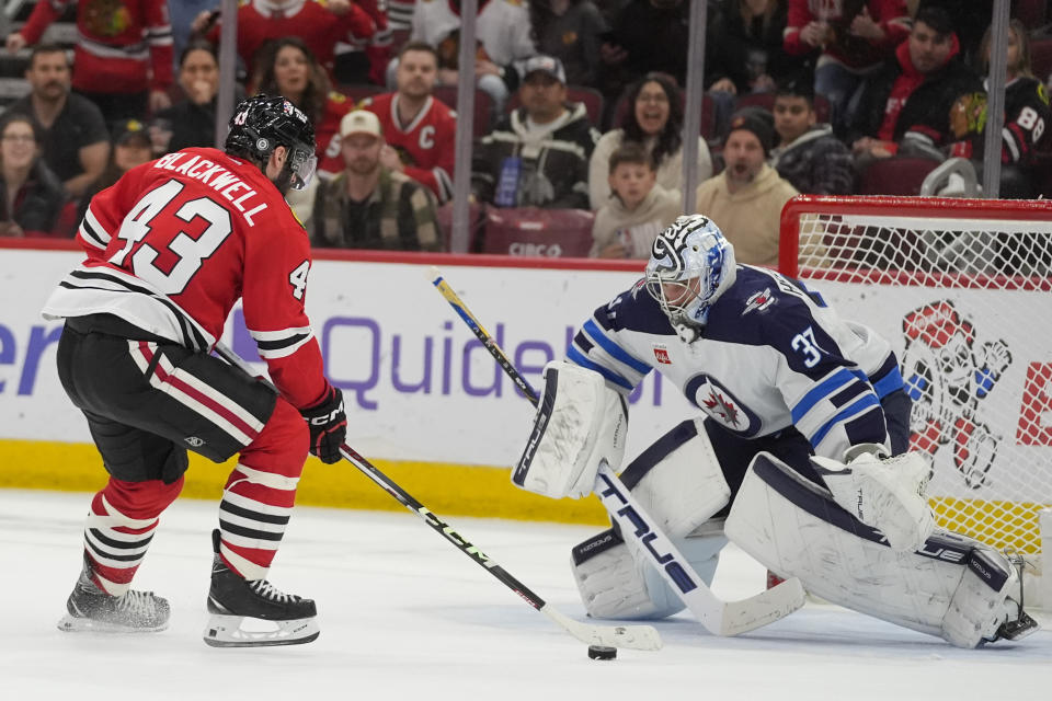 Chicago Blackhawks center Colin Blackwell (43) scores a goal against Winnipeg Jets goaltender Connor Hellebuyck, right, during the second period of an NHL hockey game Friday, Feb. 23, 2024, in Chicago. (AP Photo/Erin Hooley)