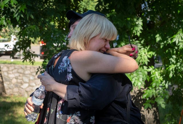 People react at a shopping center burned after a rocket attack in Kremenchuk, Ukraine, Tuesday, June 28, 2022