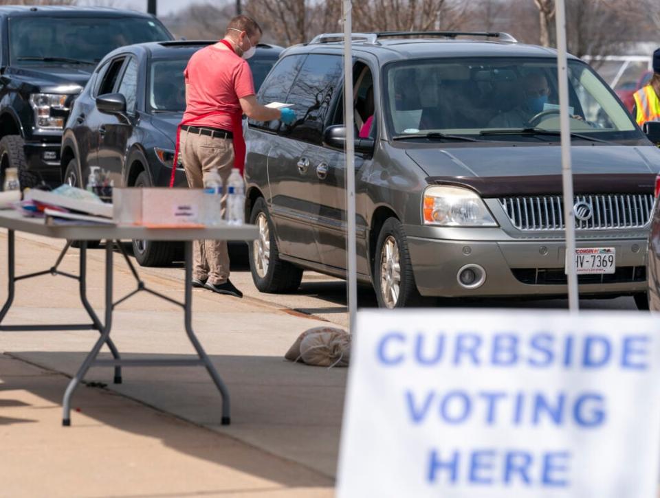 A poll worker talks to people during curbside voting on April 7, 2020 in Sun Prairie, Wisconsin. (Photo by Andy Manis/Getty Images)