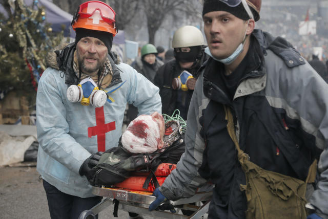 FILE- in this Thursday, Feb. 20, 2014 file photo, activists evacuate a wounded protester during clashes with police in Kiev's Independence Square, the epicenter of the country's current unrest, Kiev, Ukraine. As questions circulate about who was behind the lethal snipers that sowed death and terror in Ukraine's capital, doctors and others told the AP the similarity of bullets wounds suffered by opposition victims and police indicates the snipers were specifically trying to stoke tensions and spark a larger, angrier clash between opposition fighters and government security forces. (AP Photo/Efrem Lukatsky, file)