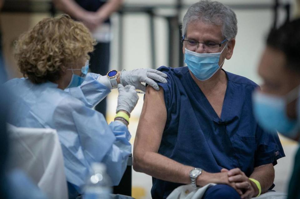 Dr. Sergio Segarra, chief medical officer, Baptist Hospital of Miami, right, gets his COVID-19 vaccine as Baptist Health began administering the first COVID-19 vaccines for its front-line healthcare workers in Miami, Florida, on Dec. 16, 2020.