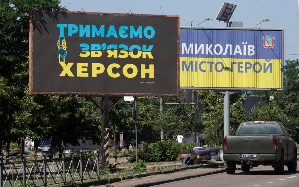 signs in Mykolaiv read 'Keep in Touch - Kherson' (left) and 'Mykolaiv - Hero City' (right) - Julian Simmonds for The Telegraph