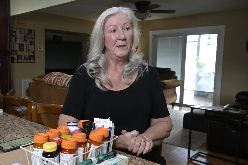 Retiree Donna Weiner, right, sits at the kitchen table with the daily prescription medications that she needs and pays over $6,000 a year through a Medicare prescription drug plan at her home, Tuesday, Oct. 5, 2021, in Longwood, Fla. Weiner supports giving Medicare authority to negotiate drug prices. Negotiating Medicare drug prices is the linchpin of President Joe Biden's ambitious health care agenda. Not only would consumers see lower costs, but savings would be plowed into other priorities such as dental coverage for retirees and lower premiums for people with plans under the Obama-era health law. (AP Photo/Phelan M. Ebenhack)