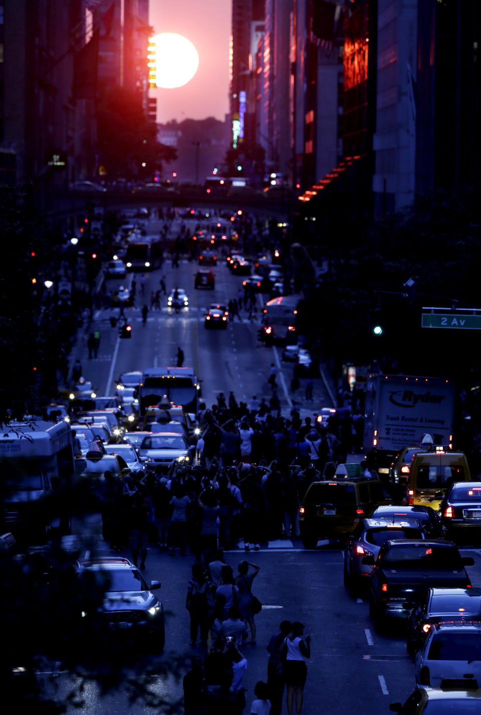 People stand in the middle of 42nd Street in New York's Manhattan borough as the sun sets through the middle of the buildings during a phenomenon known as Manhattanhenge, Wednesday, July 11, 2012. Manhattanhenge, sometimes referred to as the Manhattan Solstice, happens when the setting sun aligns with the east-to-west streets of the main street grid. The term references Stonehenge, at which the sun aligns with the stones on the solstices in England. (AP Photo/Julio Cortez)