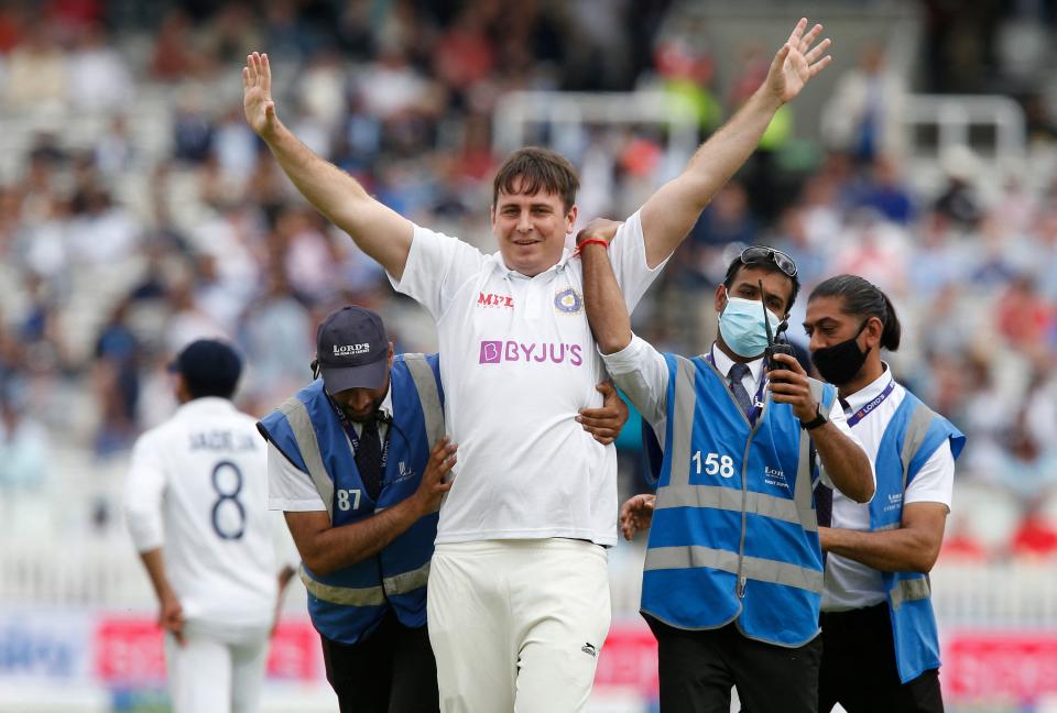 A pitch invader is escorted off of the the pitch on the third day of the second cricket Test match  between England and India at Lord's cricket ground in London on August 14, 2021. - - RESTRICTED TO EDITORIAL USE. NO ASSOCIATION WITH DIRECT COMPETITOR OF SPONSOR, PARTNER, OR SUPPLIER OF THE ECB (Photo by Ian KINGTON / AFP) / RESTRICTED TO EDITORIAL USE. NO ASSOCIATION WITH DIRECT COMPETITOR OF SPONSOR, PARTNER, OR SUPPLIER OF THE ECB (Photo by IAN KINGTON/AFP via Getty Images)