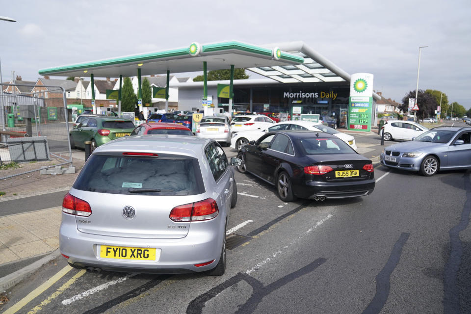 Cars queue outside a petrol station in Leicester, England, Saturday Sept. 25, 2021. The haulage industry says the U.K. is short tens of thousands of truckers, due to a perfect storm of factors including the coronavirus pandemic, an aging workforce and an exodus of European Union workers following Britain’s departure from the bloc. BP and Esso shut a handful of their gas stations this week, and motorists have formed long lines as they try to fill up in case of further disruption. (Mike Egerton//PA via AP)