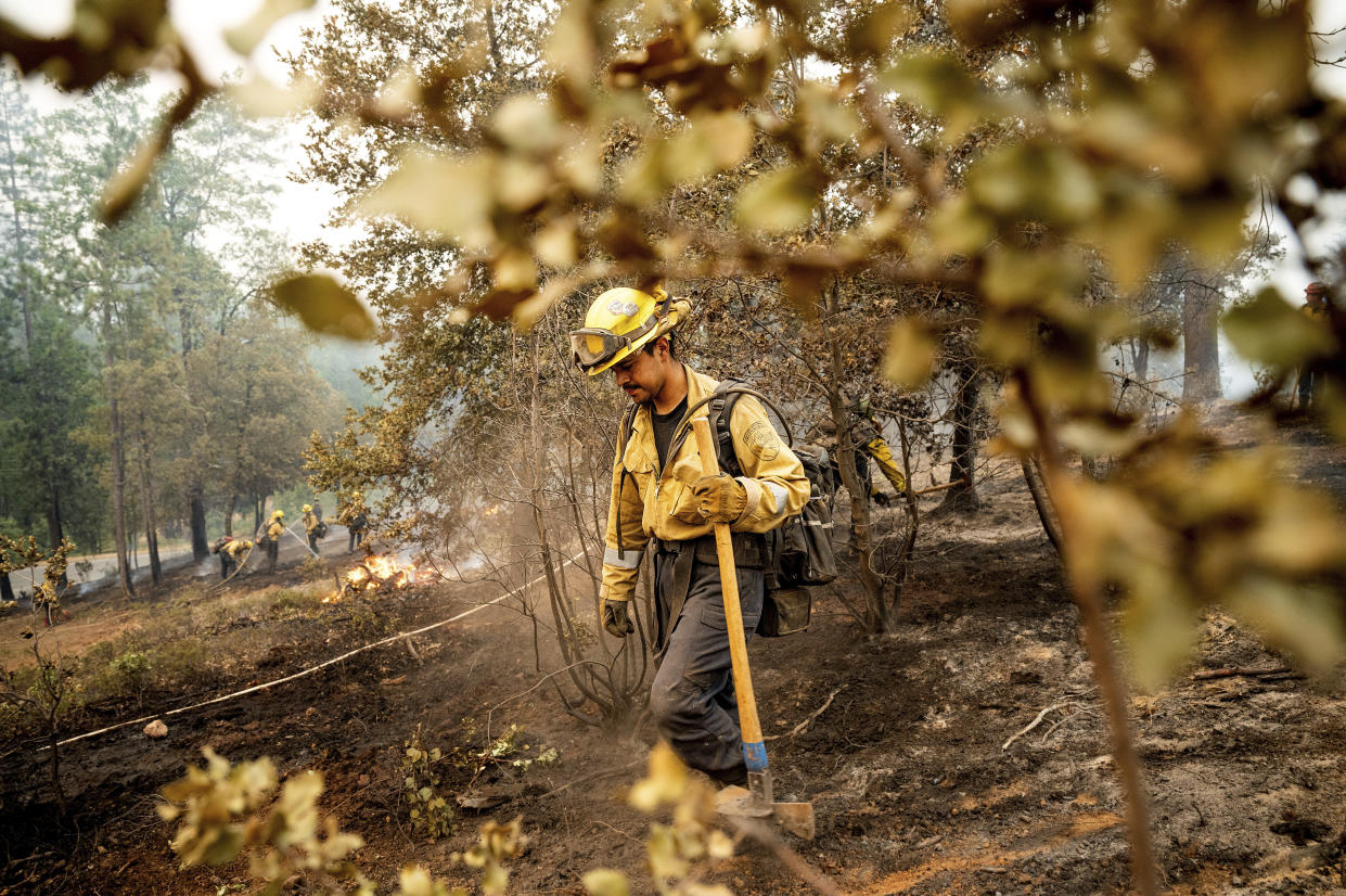 Firefighter Sergio Porras mops up hot spots while battling the Oak Fire in the Jerseydale community of Mariposa County, Calif., on Monday, July 25, 2022. He is part of Task Force Rattlesnake, a program comprised of Cal Fire and California National Guard firefighters. (AP Photo/Noah Berger)