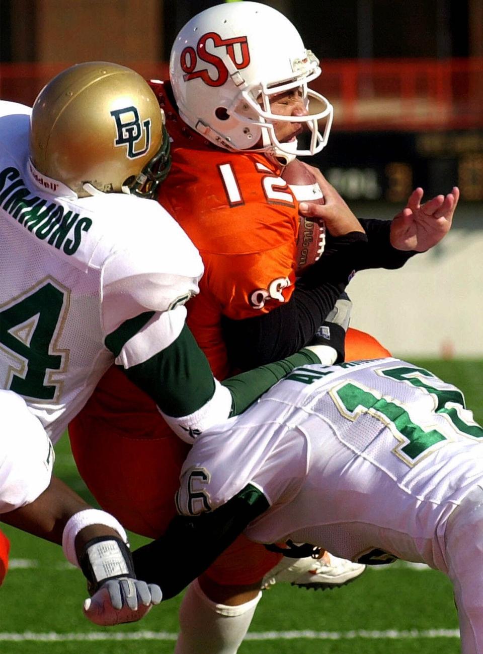 OSU quarterback Aso Pogi (12) gets hit as he crosses the goal line by Baylor's Joe Simmons (94) and Samir Al-Amin (16) on Nov. 18, 2000, in Stillwater, Okla. Pogi scored four rushing touchdowns as Oklahoma State routed Baylor 50-22.
