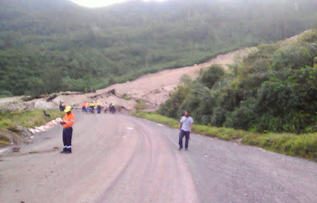 A supplied image shows locals inspecting a landslide and damage to a road located near the township of Tabubil after an earthquake that struck Papua New Guinea's Southern Highlands, February 26, 2018. Jerome Kay/Handout via REUTERS