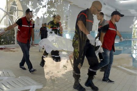 Rescuers are seen through a window as they carry the body of a tourist who was shot dead by a gunman at a beachside hotel in Sousse, Tunisia, June 26, 2015. REUTERS/Amine Ben Aziza