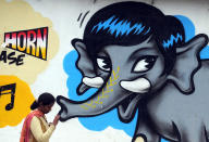 An Indian woman walks past a wall mural depicting an elephant in Bangalore. <br> AFP PHOTO/Dibyangshu SARKAR