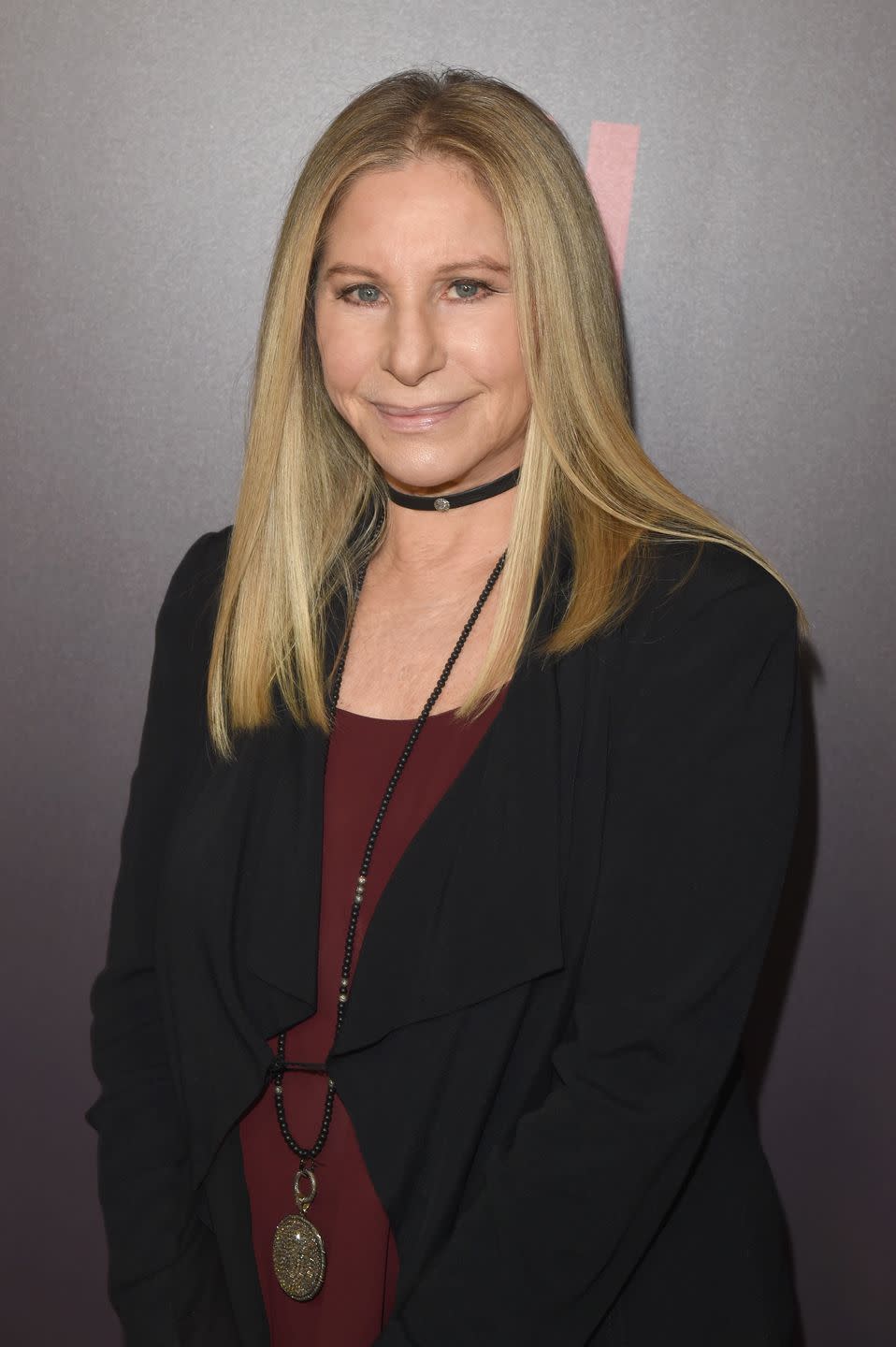 barbra streisand wearing a red top, black blazer and necklace