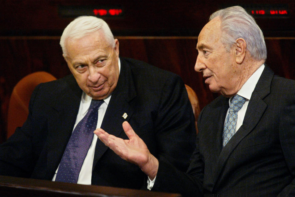 FILE - In this Wednesday, Jan. 12, 2005 file photo, Israeli Prime Minister Ariel Sharon, left, speaks with second vice premier and Labor party leader Shimon Peres prior to a session in the Knesset, Israel's parliament, for the budget vote, in Jerusalem. Sharon, the hard-charging Israeli general and prime minister who was admired and hated for his battlefield exploits and ambitions to reshape the Middle East, died Saturday, Jan. 11, 2014. The 85-year-old Sharon had been in a coma since a debilitating stroke eight years ago.(AP Photo/Oded Balilty, FIle)