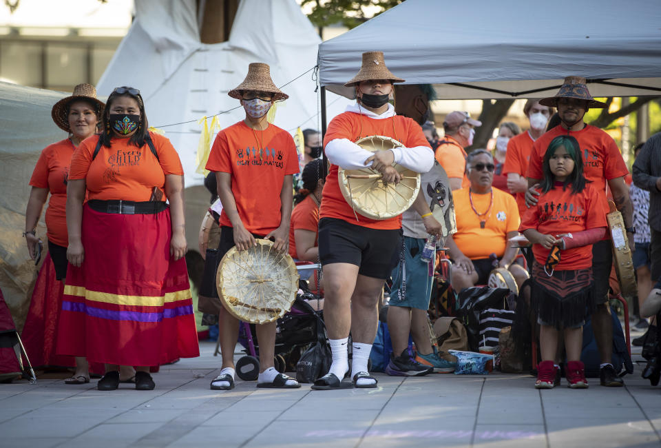 People listen during a ceremony and vigil for the 215 children whose remains were found buried at the former Kamloops Indian Residential School, in Vancouver, British Columbia, on National Indigenous Peoples Day, Monday, June 21, 2021. (Darryl Dyck/The Canadian Press via AP)