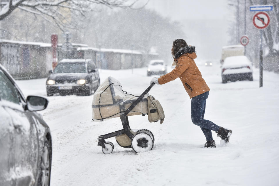 A woman pushes a pram across the street during heavy snowfall in Bratislava, Slovakia, Tuesday, Jan. 8, 2019. Cold weather has engulfed many parts of Europe Tuesday. (Pavol Zachar/TASR via AP)