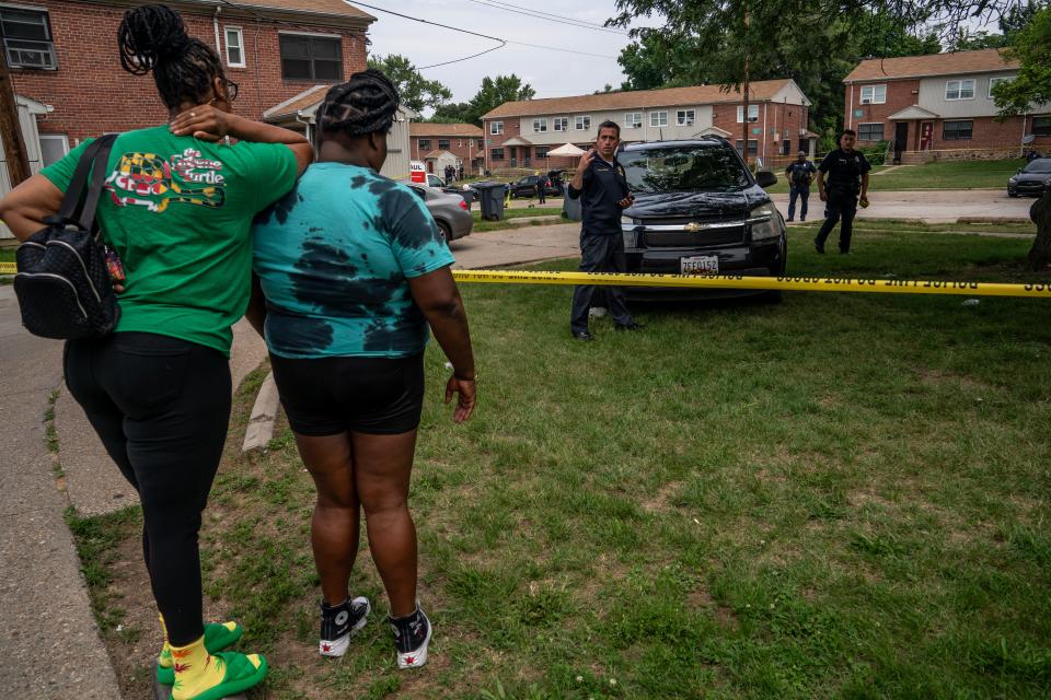 Residents watch as Baltimore Police investigate the site of a mass shooting in the Brooklyn Homes neighborhood on July 2, 2023 in Baltimore, Maryland. At least two people were killed and 28 others were wounded  during the shooting at a block party on Saturday night.