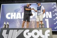 En foto del 14 de mayo del 2023, l campeón individual Dustin Johnson y su caddie Austin Johnson celebra en el podio durante la ceremonia de trofeo en el torneo LIV Golf Tulsa e Cedar Ridge Country Club. El martes 6 de junio del 2023, la PGA, la Gira Europa se unirán en una empresa comercial con el fondo saudí y con lo que llega a su fin la demanda de LIV Golf. (Amy Kontras/LIV Golf via AP)