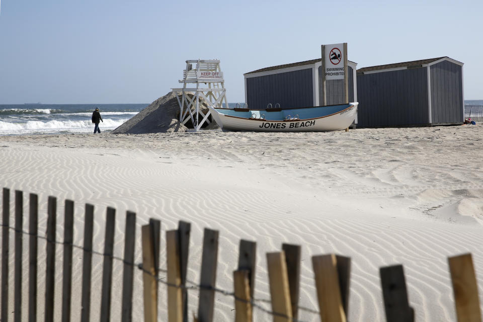 A person walks by the water during the coronavirus outbreak, Thursday, May 21, 2020, at Jones Beach in Wantagh, New York. As pandemic lockdowns ease across the United States, millions of Americans are set to take tentative steps outdoors to celebrate Memorial Day, the traditional start of summer. But public health officials are concerned that if people congregate in crowds or engage in other risky behaviors, the long weekend could cause the coronavirus to come roaring back. (AP Photo/Kathy Willens)