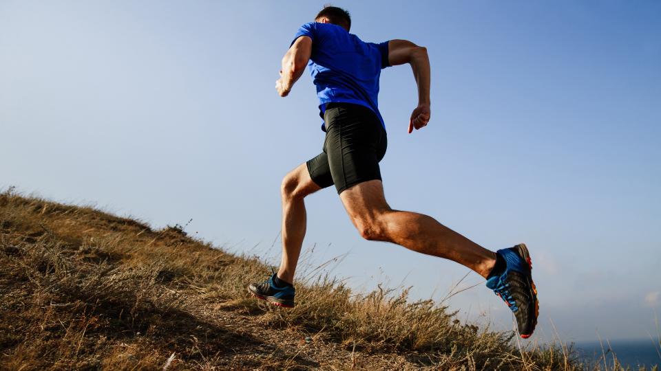 Best strength exercises: man running uphill outdoors in the countryside in the sunshine