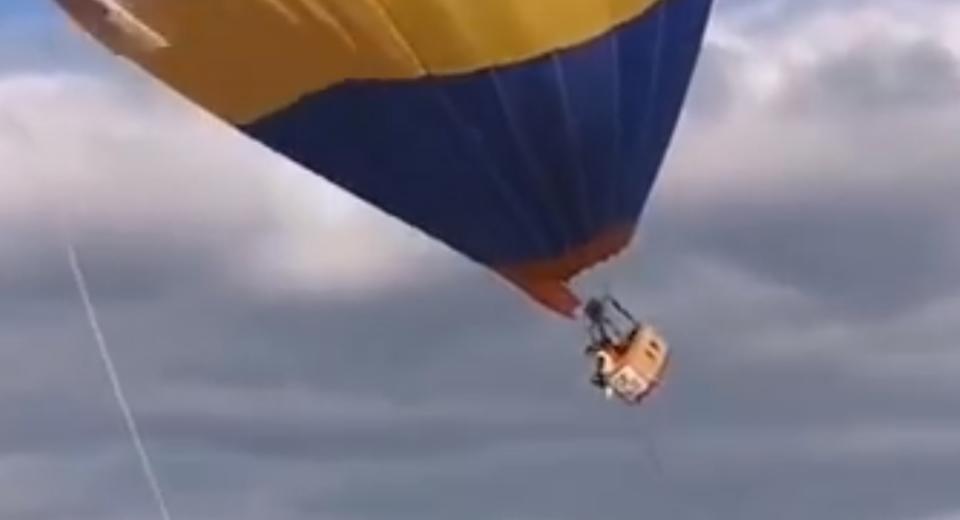熱氣球突然升空，導致一名工作人員被掛在籃子上，雙腳懸空瘋狂掙扎。（圖／翻攝自漩渦視頻微博）