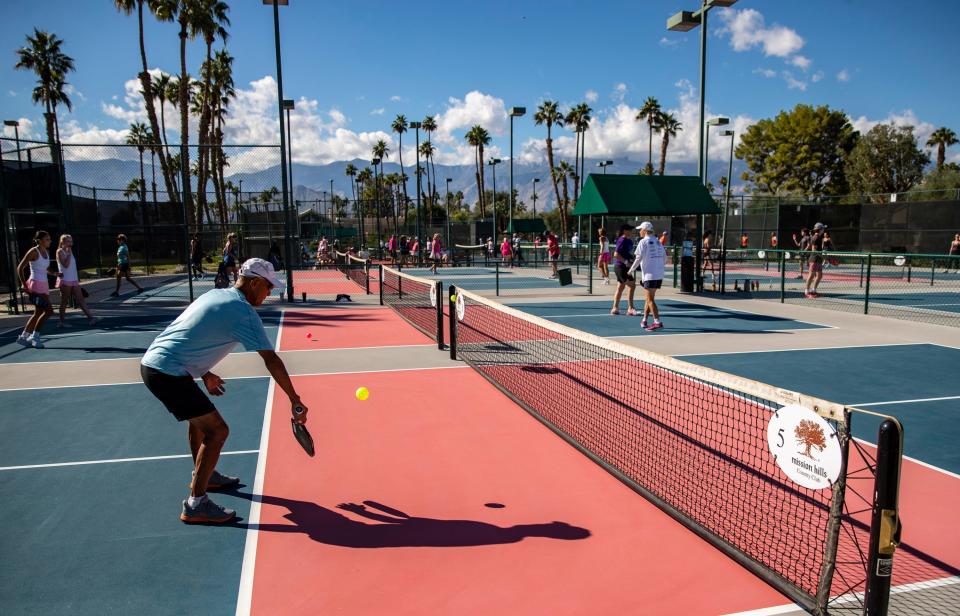 Players warm up while others play early round matches during the Pink Pickleball Charity Tournament at Mission Hills Country Club in Rancho Mirage, Calif., Saturday, Nov. 18, 2023.