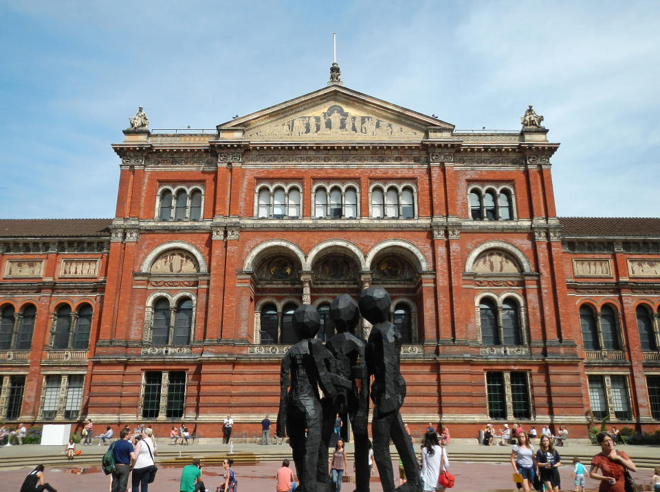 Silhouetted figures in front of a historical building with visitors milling around