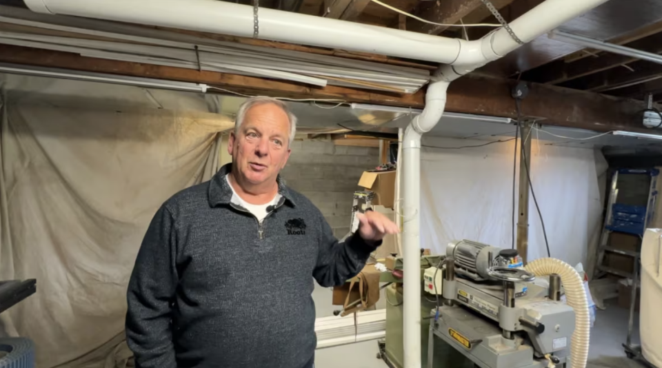 Bob Barnes stands next to his ventilation system in his basement that blows the radon gas out of his home. (Meg Roberts/CBC)