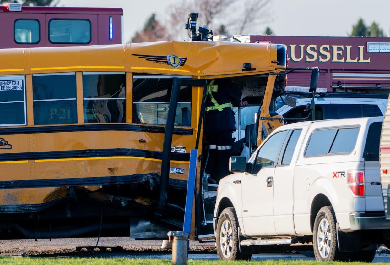 An officer from the Ontario Provincial Police (OPP) stands inside a school bus as they work the scene of a crash involving the bus and a truck in Russell, east of Ottawa, on Monday.  (Spencer Colby/The Canadian Press - image credit)