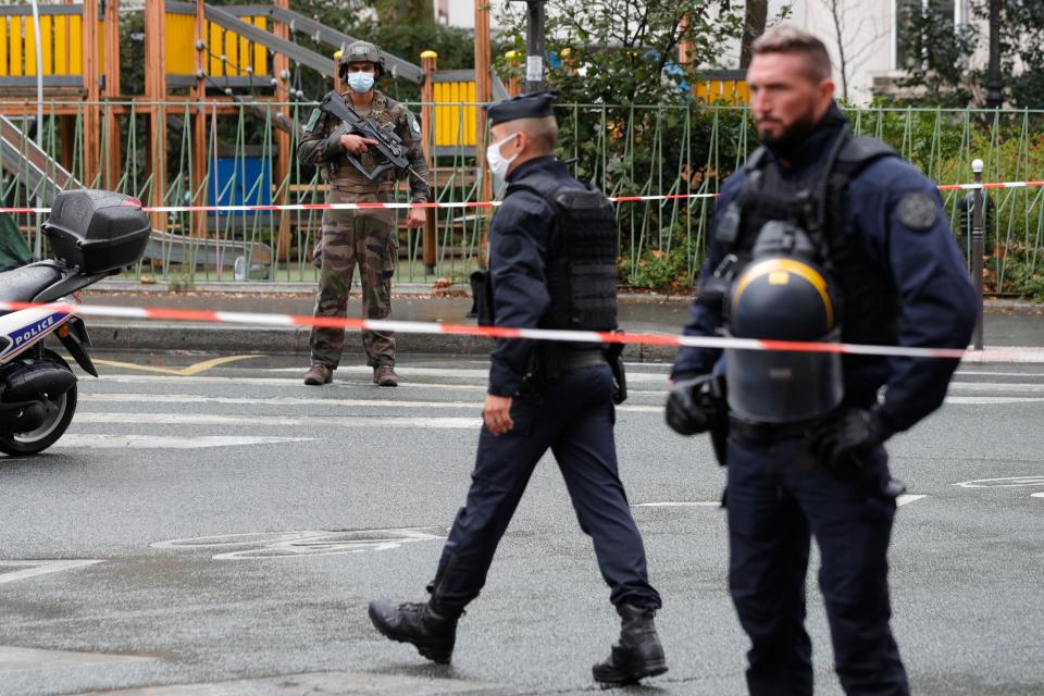 An armed French soldier (background) stands guard as policemen secure the area after several people were injured near the former offices of the French satirical magazine Charlie Hebdo following an attack by a man wielding a knife in the capital Paris on September 25, 2020. - Four people were injured, two seriously, in a knife attack in Paris on September 25, 2020, near the former offices of French satirical magazine Charlie Hebdo, a source close to the investigation told AFP. Two of the victims were in a critical condition, the Paris police department said, adding two suspects were on the run. The stabbing came as a trial was underway in the capital for alleged accomplices of the authors of the January 2015 attack on the Charlie Hebdo weekly that claimed 12 lives. (Photo by GEOFFROY VAN DER HASSELT / AFP) (Photo by GEOFFROY VAN DER HASSELT/AFP via Getty Images)