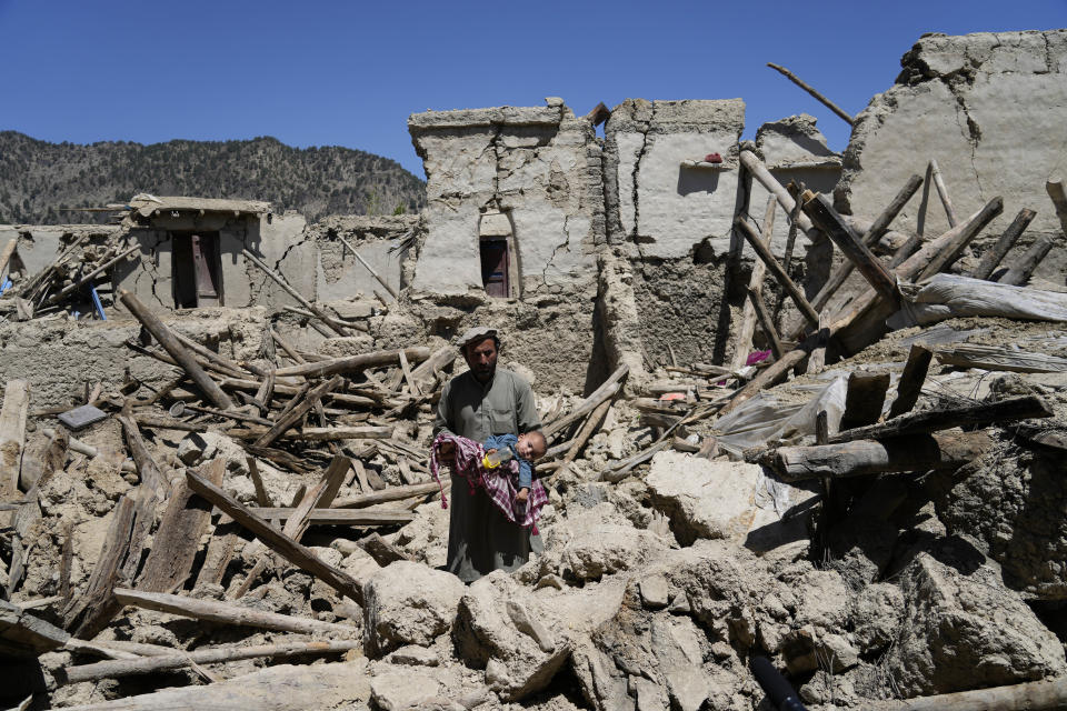 Afghan man carries his child amid destruction after an earthquake in Gayan village, in Paktika province, Afghanistan, Friday June 24, 2022. A powerful earthquake struck a rugged, mountainous region of eastern Afghanistan early Wednesday, flattening stone and mud-brick homes in the country's deadliest quake in two decades, the state-run news agency reported. (AP Photo/Ebrahim Nooroozi)