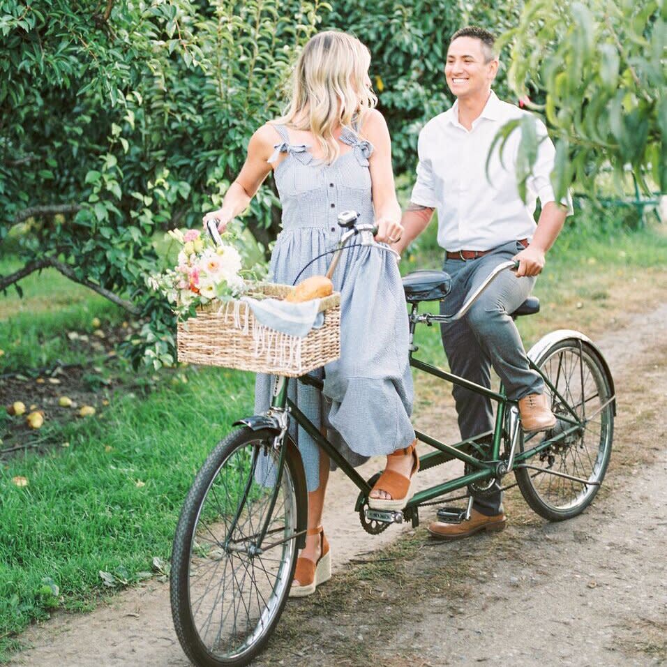 engagement photo idea of couple on a bike in an orchard