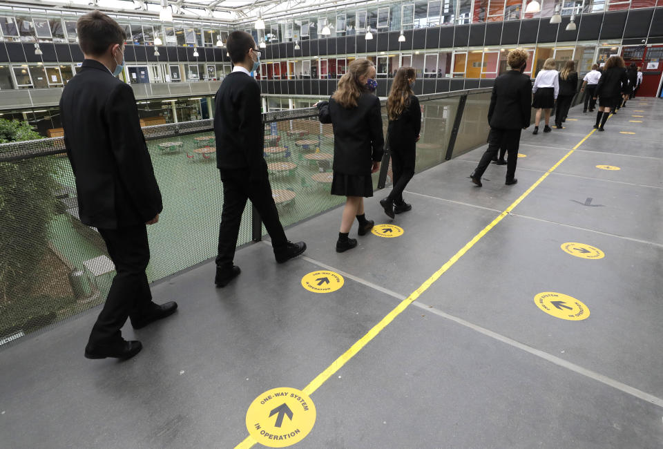 Pupils follow social distancing signs as they walk along a corridor at Kingsdale Foundation School in London, Thursday, Sept. 3, 2020. Schools in England are starting to reopen with special measures in place to deal with Coronavirus. (AP Photo/Kirsty Wigglesworth)