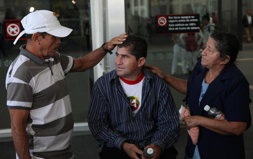 Sea survivor Jose Salvador Alvarenga, center, is flanked by his father Jose Ricardo and mother Maria Julia, before entering the waiting hall for national departures, after arriving at the airport in Mexico City, Friday, March 14, 2014. The Salvadoran fisherman, who was lost at sea for 13 months, traveled from El Salvador to Mexico to fulfill a promise he made to his dead sea mate, Mexican Ezequiel Cordoba. Alvarenga said Cordoba died a month into their ordeal because he couldn't stomach the diet of raw fish, turtles and birds. (AP Photo/Marco Ugarte)