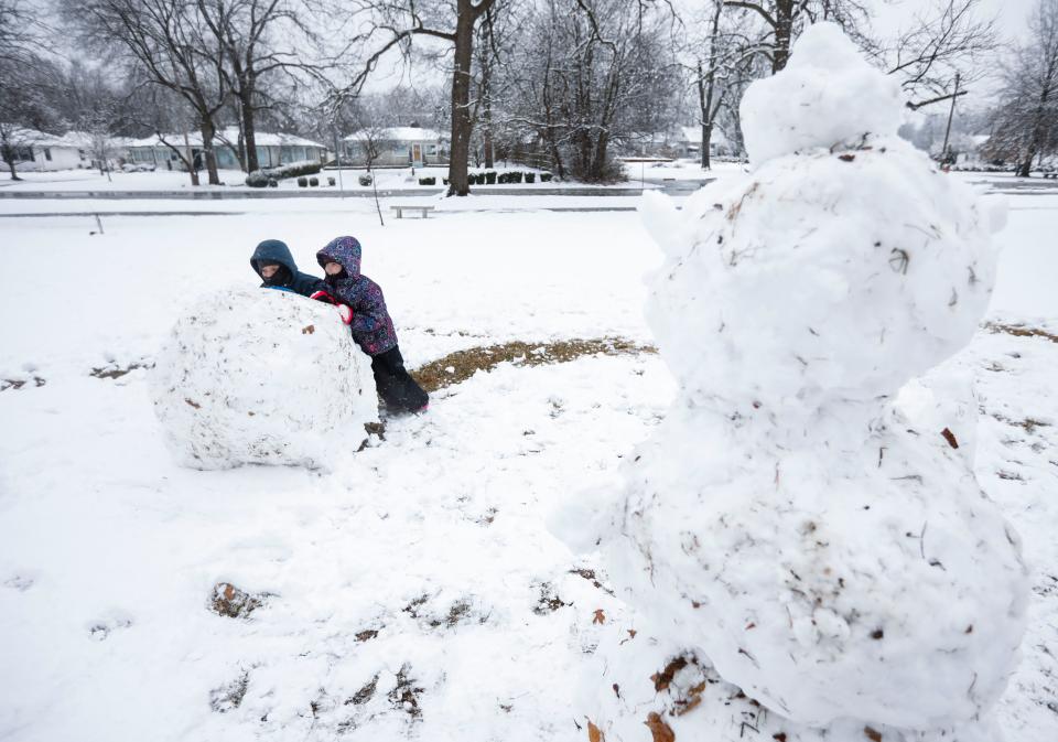 Gregory, 10, and Allison, 7, Soules roll a ball of snow in Phelps Grove Park as they build a second snowman on Monday, Feb.12, 2024.