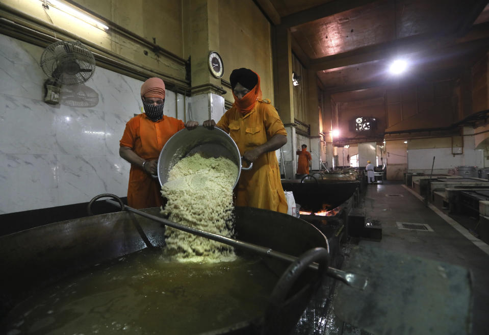 A Sikh volunteer pours rice into a giant vessel in the kitchen hall of the Bangla Sahib Gurdwara in New Delhi, India, Sunday, May 10, 2020. The Bangla Sahib Gurdwara has remained open through wars and plagues, serving thousands of people simple vegetarian food. During India's ongoing coronavirus lockdown about four dozen men have kept the temple's kitchen open, cooking up to 100,000 meals a day that the New Delhi government distributes at shelters and drop-off points throughout the city. (AP Photo/Manish Swarup)