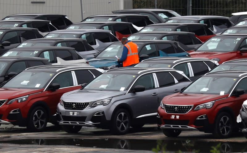 A worker checks cars at the PSA Peugeot Citroen plant in Poissy, near Paris