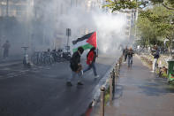 A demonstrator holding a Palesnian flag crosses a street during a banned protest in support of Palestinians in the Gaza Strip, Saturday, May, 15, 2021 in Paris. Marches in support of Palestinians in the Gaza Strip were being held Saturday in a dozen French cities, but the focus was on Paris, where riot police got ready as organizers said they would defy a ban on the protest. (AP Photo/Michel Euler)