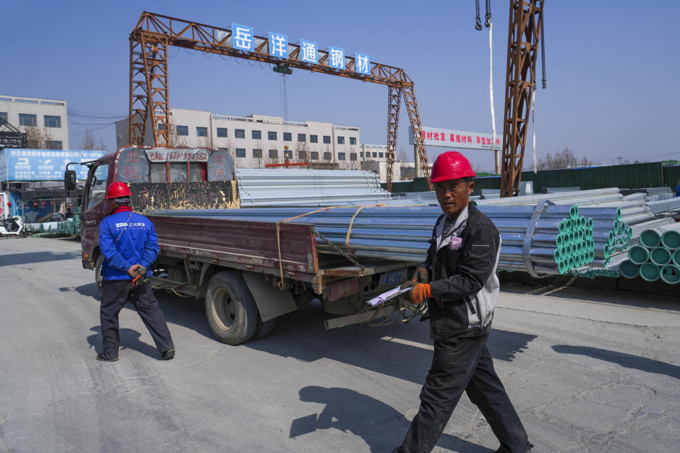 A worker walks past steel pipes loaded on a truck in Xiongan in northern China's Hebei province on March 14, 2024. China’s first generation of migrant workers played an integral role in the country's transformation from an impoverished nation to an economic powerhouse. Now, they're finding it hard to find work, both because they're older and the economy is slowing. (AP Photo/Tatan Syuflana)