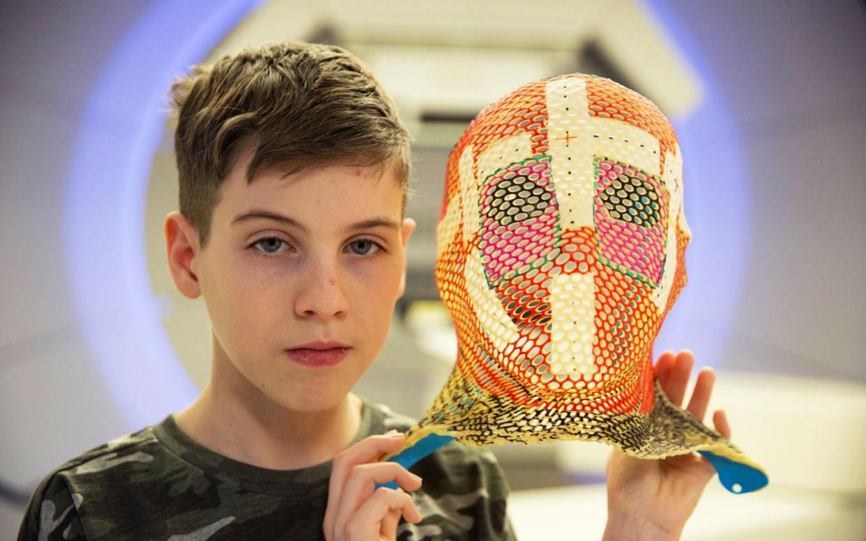 15-year-old Mason holds the mask he wore for his Proton Therapy - BBC