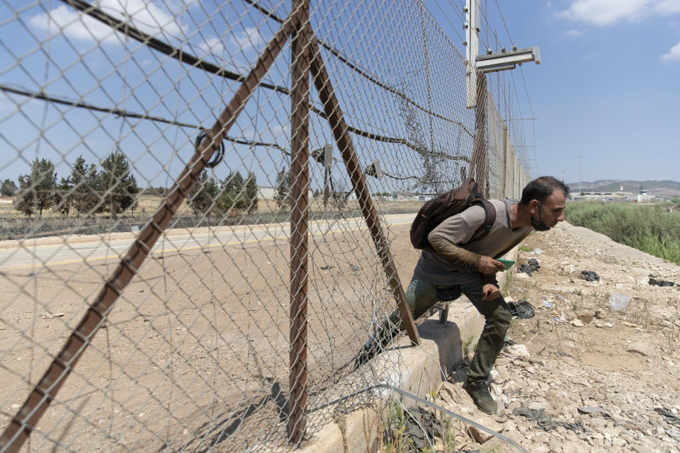A Palestinian laborer crosses through a damaged section of the Israeli separation fence, returning home after a days work in Israel, in the West Bank village of Jalameh, near Jenin, Monday, Sept. 6, 2021. Israel launched a massive manhunt in the country's north and the occupied West Bank early Monday after six Palestinian prisoners tunneled out of their cell and escaped overnight from a high-security facility in an extremely rare breakout. (AP Photo/Nasser Nasser)